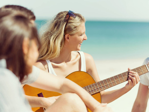 Beautiful young woman playing guitar on beach - Valokuva, kuva