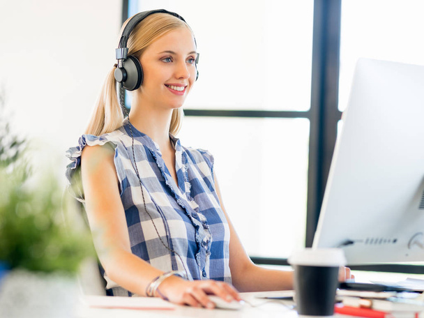 Young woman working in office with headphones - Foto, imagen