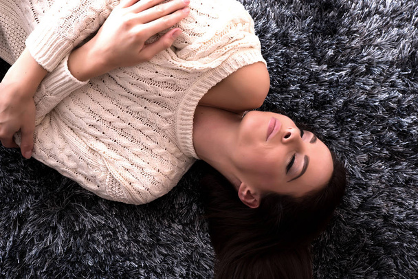 Young, beautiful woman lying on the carpet - 写真・画像