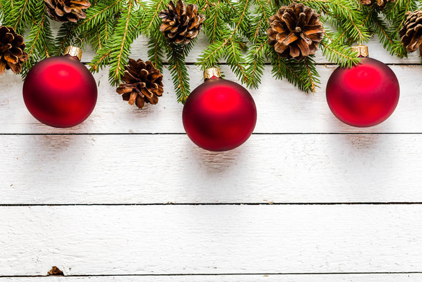 Bordo natalizio con palline rosse su ramoscelli di abete su sfondo bianco in legno, vista dall'alto
 - Foto, immagini