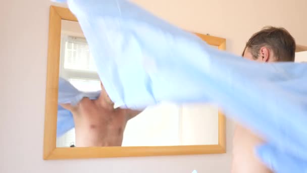Μια εύθυμος τύπος χαριτωμένο φορέματα μπροστά από έναν καθρέφτη και χαμόγελα στο το είδωλό του. 4k, αργή κίνηση - Πλάνα, βίντεο