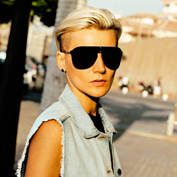 Stylish blonde in trend sunglasses and denim clothes in the city - Foto, Bild