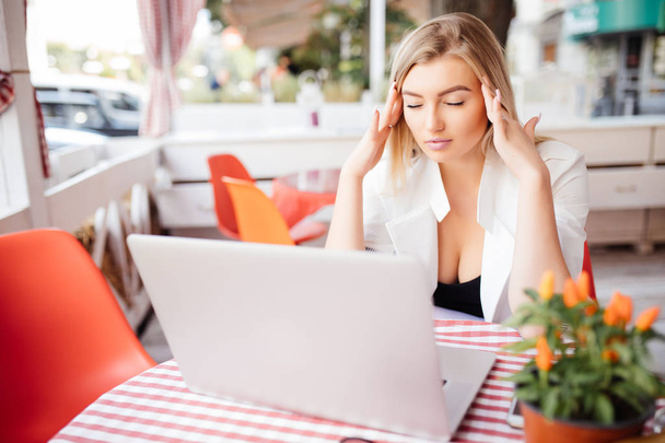 Mujer de negocios que tiene dolor de cabeza mientras trabaja usando computadora portátil
. - Foto, imagen