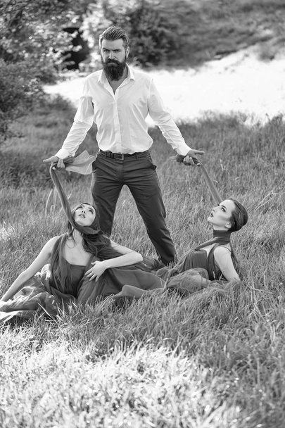 Bearded man and two women on grass - 写真・画像