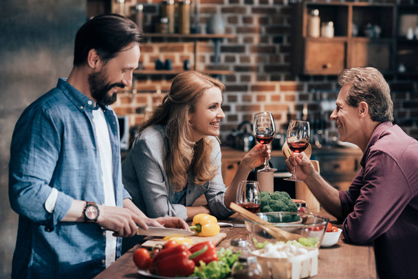friends drinking wine while cooking dinner - Foto, Imagem