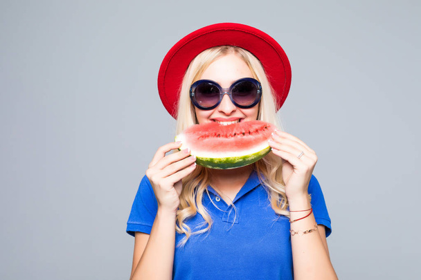 junge hübsche Frauen halten eine Scheibe Wassermelone in den Händen und lächeln glücklich, sommerliches Konzept und Stimmung, vor grauem Hintergrund - Foto, Bild
