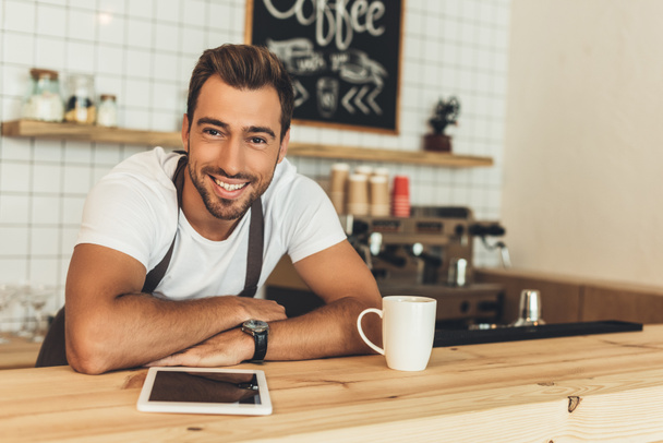 smiling barista at counter with tablet - Photo, Image
