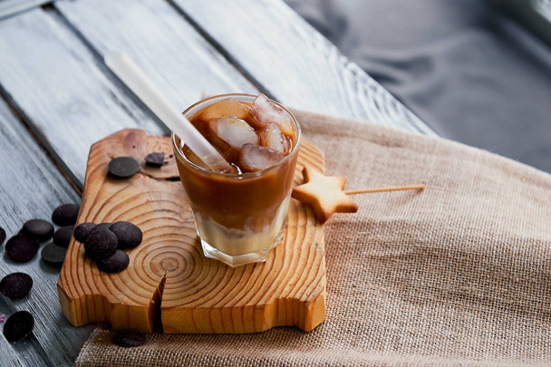 The Hong Kong iced coffee in a glass, with a straw. interesting wooden background - Фото, изображение