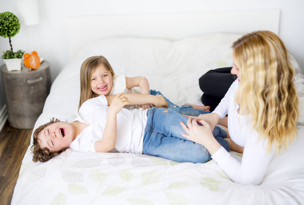 Portrait of a happy mother and her children lying on a bed - Foto, afbeelding