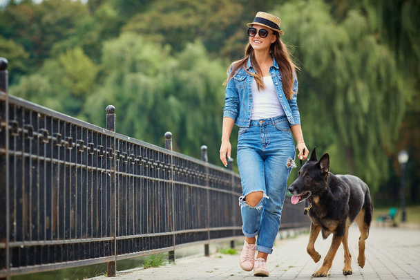 A young girl is walking with a dog in the park. - Foto, imagen