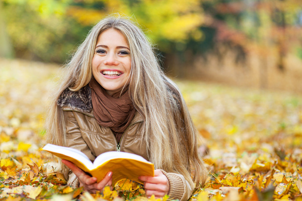Young woman reading in a park in autumn - Photo, Image