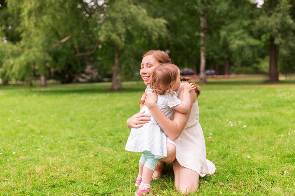 happy mother hugging baby girl at summer park - 写真・画像
