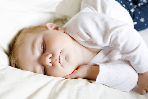 Χαριτωμένο αξιολάτρευτο κοριτσάκι 6 μηνών κοιμάται γαλήνια στο κρεβάτι - Φωτογραφία, εικόνα