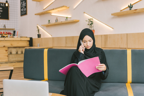 Muslimin liest Magazin im Café - Foto, Bild