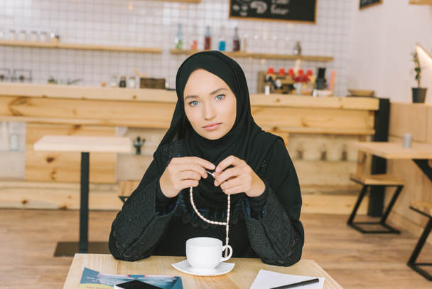 Mulher muçulmana sentada no café
 - Foto, Imagem
