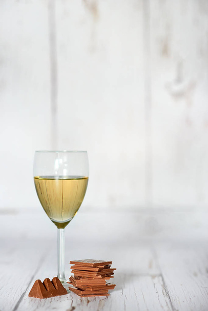 Ποτήρι λευκό κρασί με σοκολάτα - εστίαση στην γωνία - Φωτογραφία, εικόνα