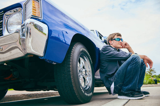Portrait of pensive young man squatting at his car - Zdjęcie, obraz