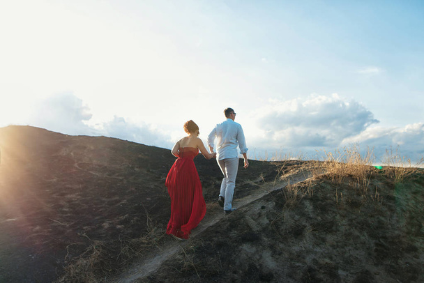 Young couple climbs top of a mountain and enjoying sunset - Fotografie, Obrázek