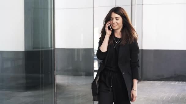Beautiful young businesswoman talking on a phone and walking - Felvétel, videó