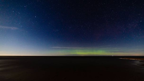 intense northern lights aurora borealis over beach  - Photo, Image