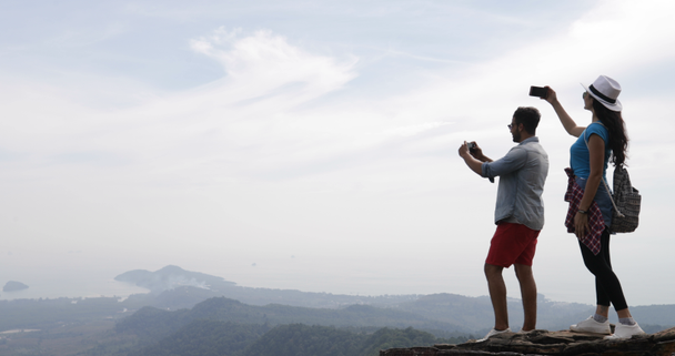 Couple de touristes prenant des photos du paysage du sommet de la montagne sur les téléphones intelligents cellulaires, jeune homme et femme Voyage
 - Séquence, vidéo