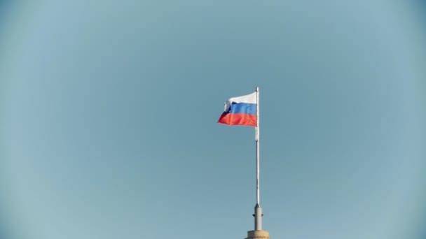 Ρωσική σημαία φτερουγίζει στον αέρα μπροστά από το μπλε του ουρανού, αργή κίνηση - Πλάνα, βίντεο