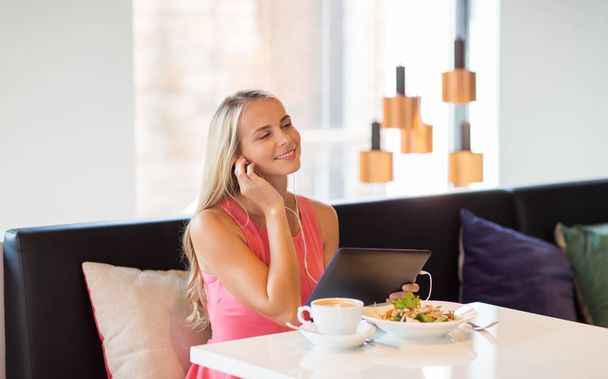 happy young woman with tablet pc at restaurant - Foto, Imagen