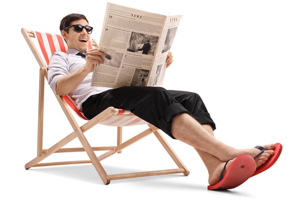 Businessman sitting in a deck chair and reading a newspaper - Foto, afbeelding