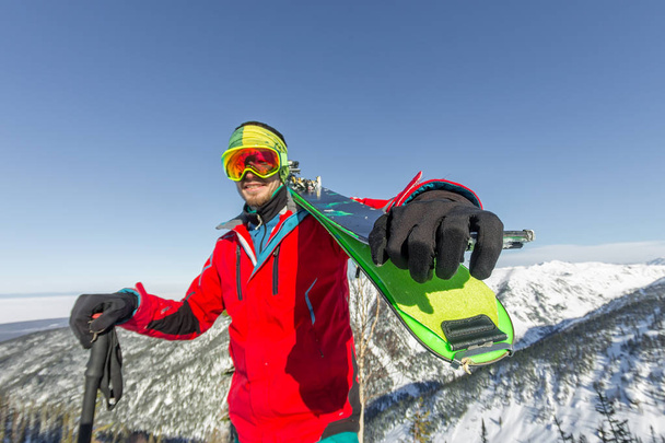 Portrait young man ski goggles holding ski in the mountains - Foto, Bild