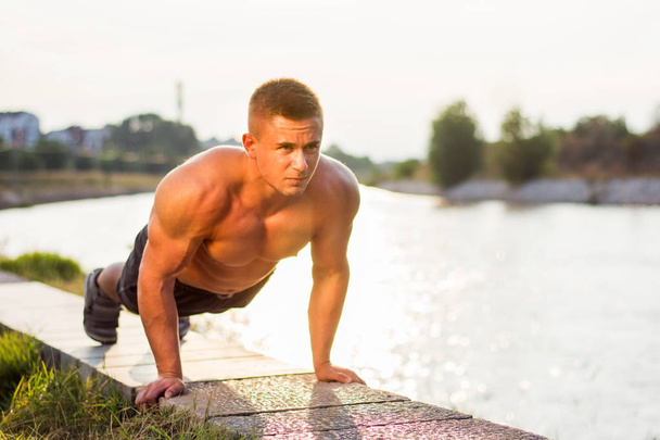 Man doing push ups by the river - Photo, Image