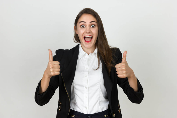 Thumb up. Happy young businesswoman isolated on gray background. - Photo, Image