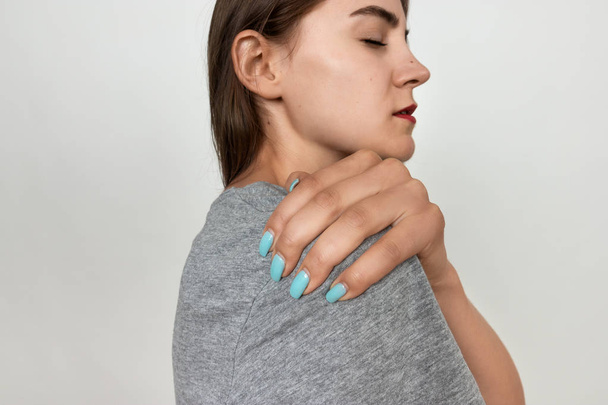 Mujer joven con dolor de hombro. Concepto de dolor de cerca
 - Foto, Imagen