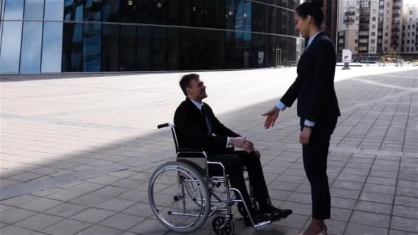 Empresaria estrechando la mano con colega discapacitado al aire libre
 - Metraje, vídeo