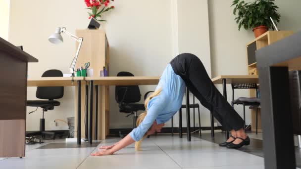 Vrouwelijke uitvoerend uitvoeren van yoga op haar werk in office. 4k, slow-motion - Video