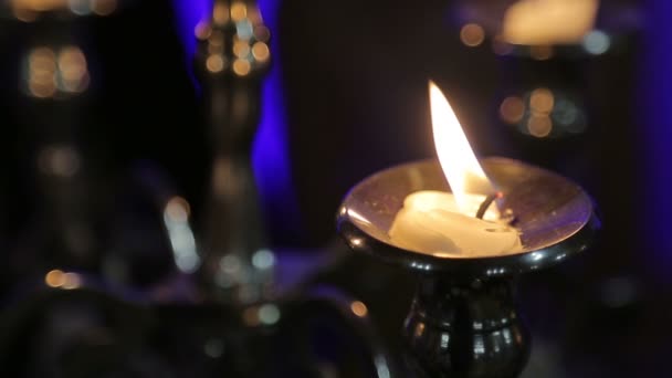 One candle on a table on a black background blazes - Felvétel, videó