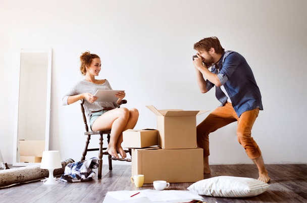 Young couple moving in new house, taking photos. - Φωτογραφία, εικόνα