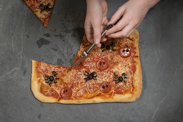 Affettare a mano la pizza di Halloween utilizzando Pizza Cutter
 - Foto, immagini