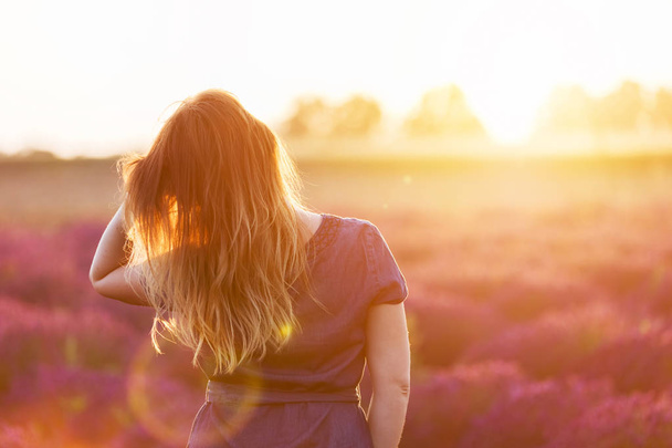 Молода жінка торкається її довге волосся, дивлячись на лавандове поле
  - Фото, зображення