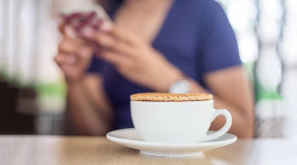 stroopvohveli kuumalla kahvikupilla ja hämärä nainen
 - Valokuva, kuva