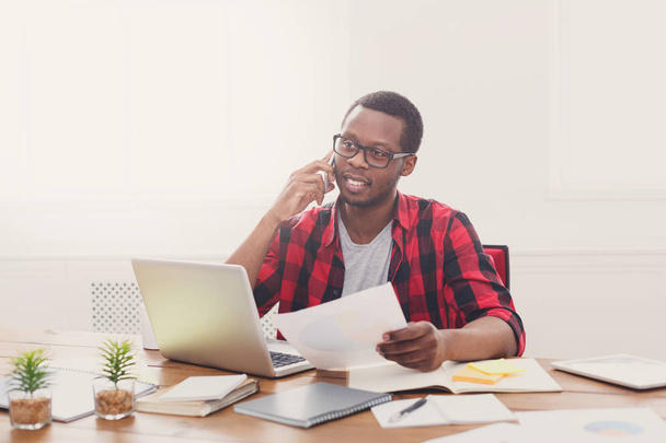 Mladá černá podnikatel čtení dokumentů a mluvit na mobilních zařízeních v moderní bílé úřadu - Fotografie, Obrázek