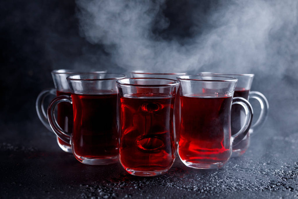 red cocktail with ice vapor. red cold tea with steam on a black background. - Фото, зображення