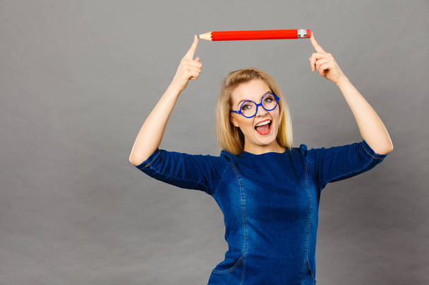 Smiling woman holds big pencil in hand - Fotoğraf, Görsel