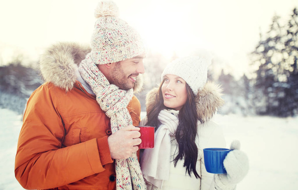 happy couple with tea cups over winter landscape - Valokuva, kuva