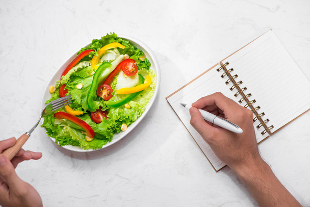 otepad, penna e forchetta con insalata fresca
 - Foto, immagini