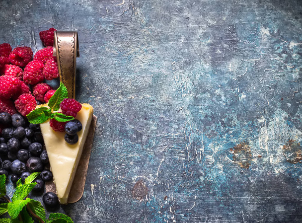 Cheesecake with berries on blue slate background.  - Zdjęcie, obraz