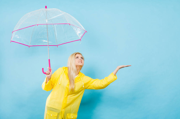 Woman wearing raincoat holding umbrella checking weather - Photo, image