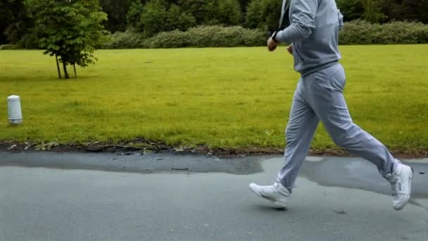 Člověk běží v zelených parkwoods tréninku a podívat se na paže hodiny - Záběry, video