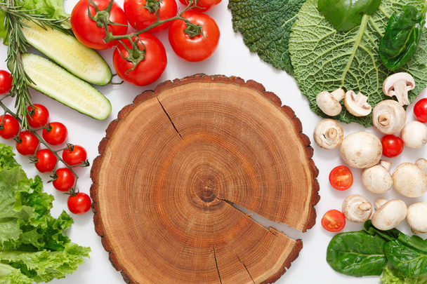 Brown wood cutting board, border of fresh vegetables on white background with copy space - Фото, изображение