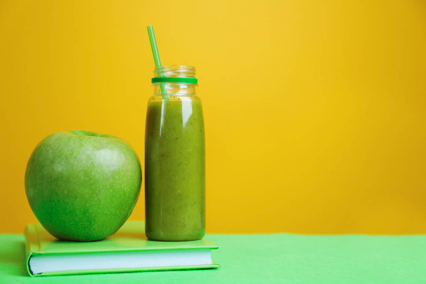 Bottle with fresh healthy smoothie, green apple and book - Photo, image