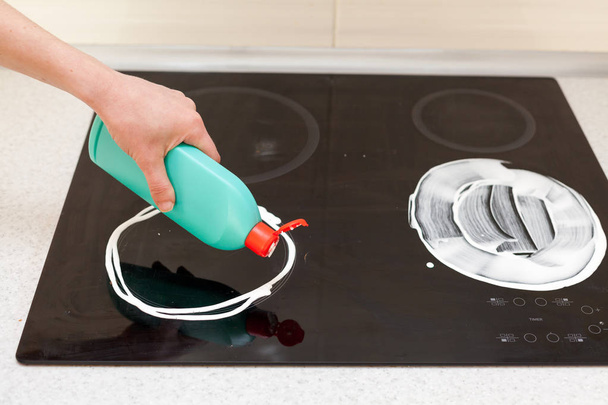 Woman hands with bottle of cleaning detergent for metal sink in kitchen - Photo, image